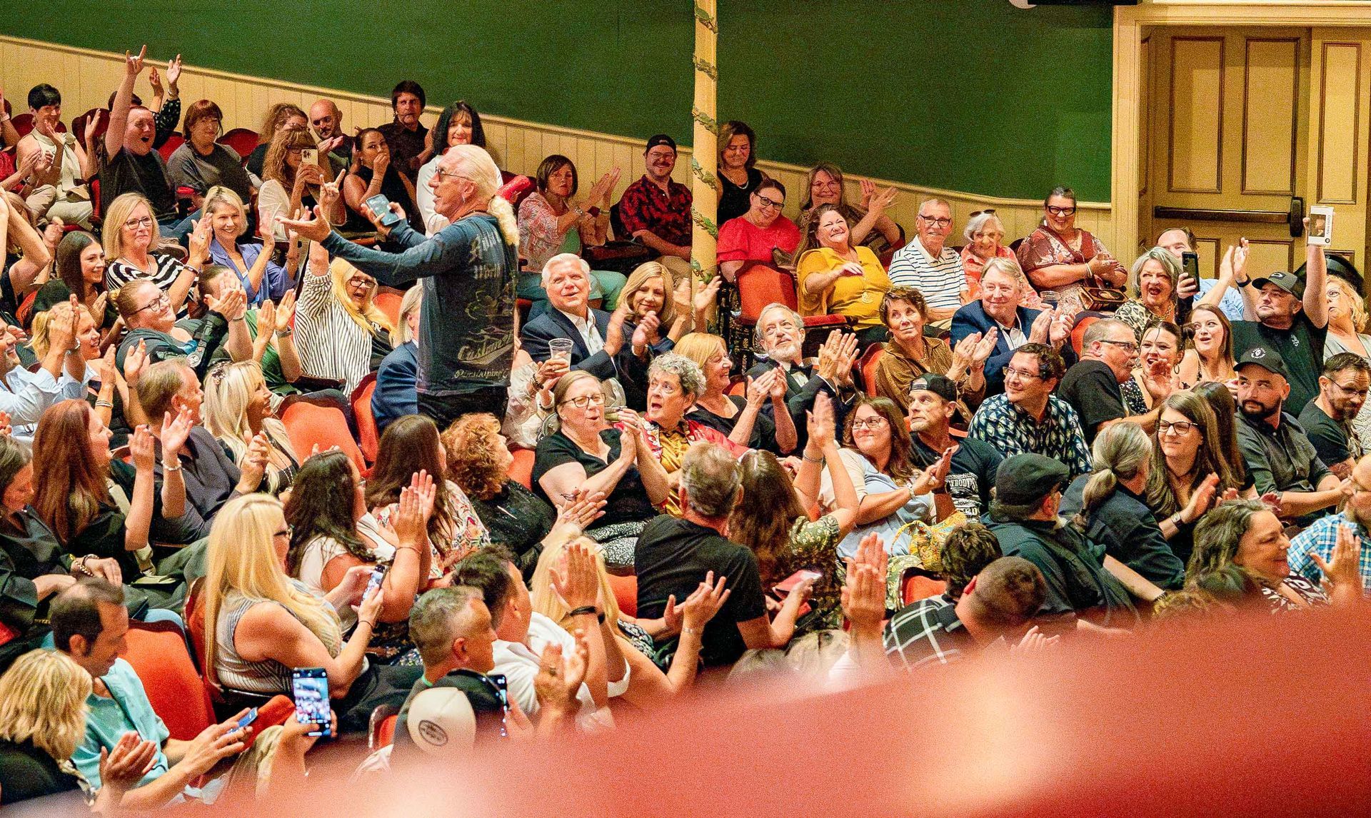 Crowded gym bleachers filled with cheering spectators in colorful shirts and jackets