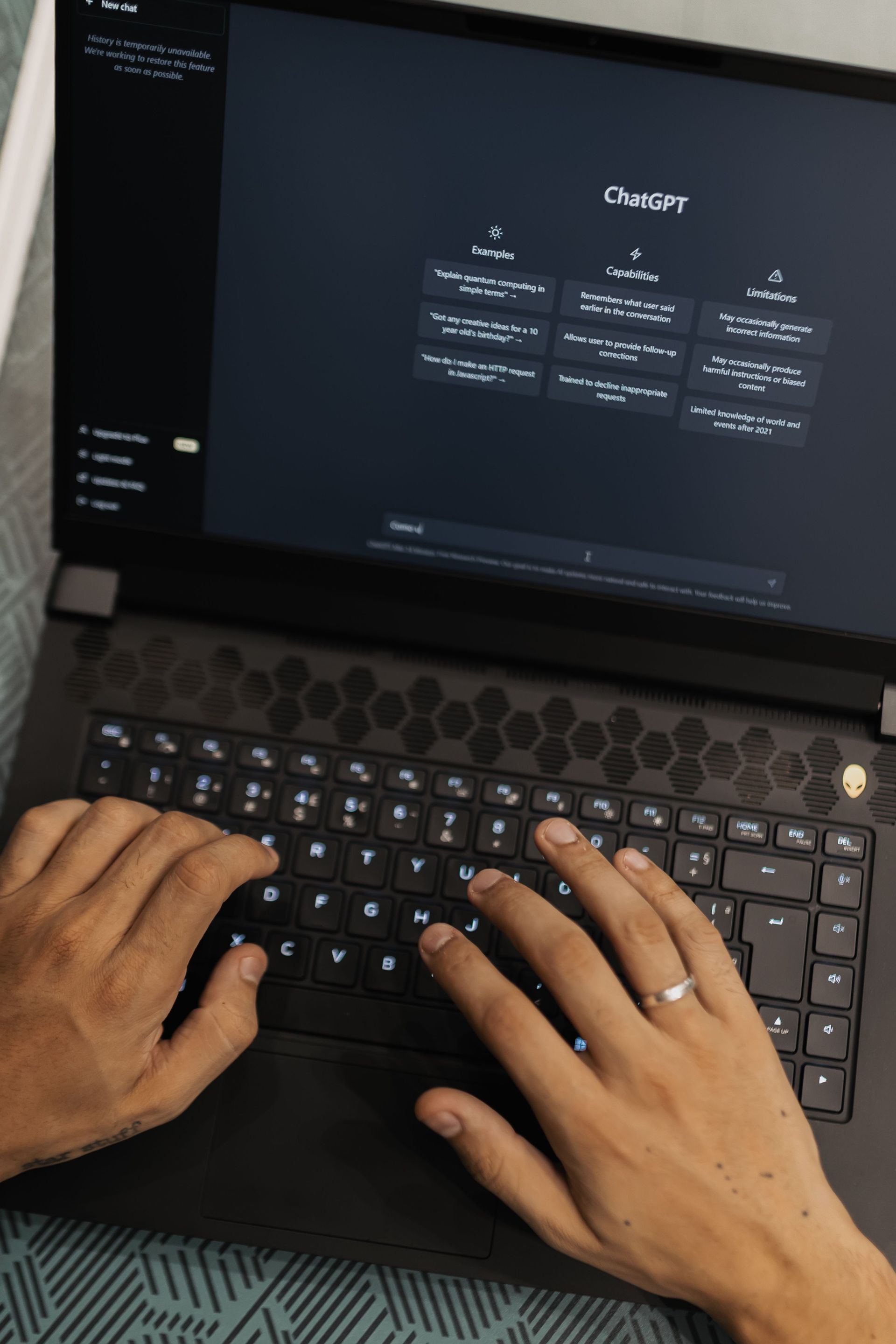 Hands typing on a laptop showing a dark-themed webpage with a chart on screen