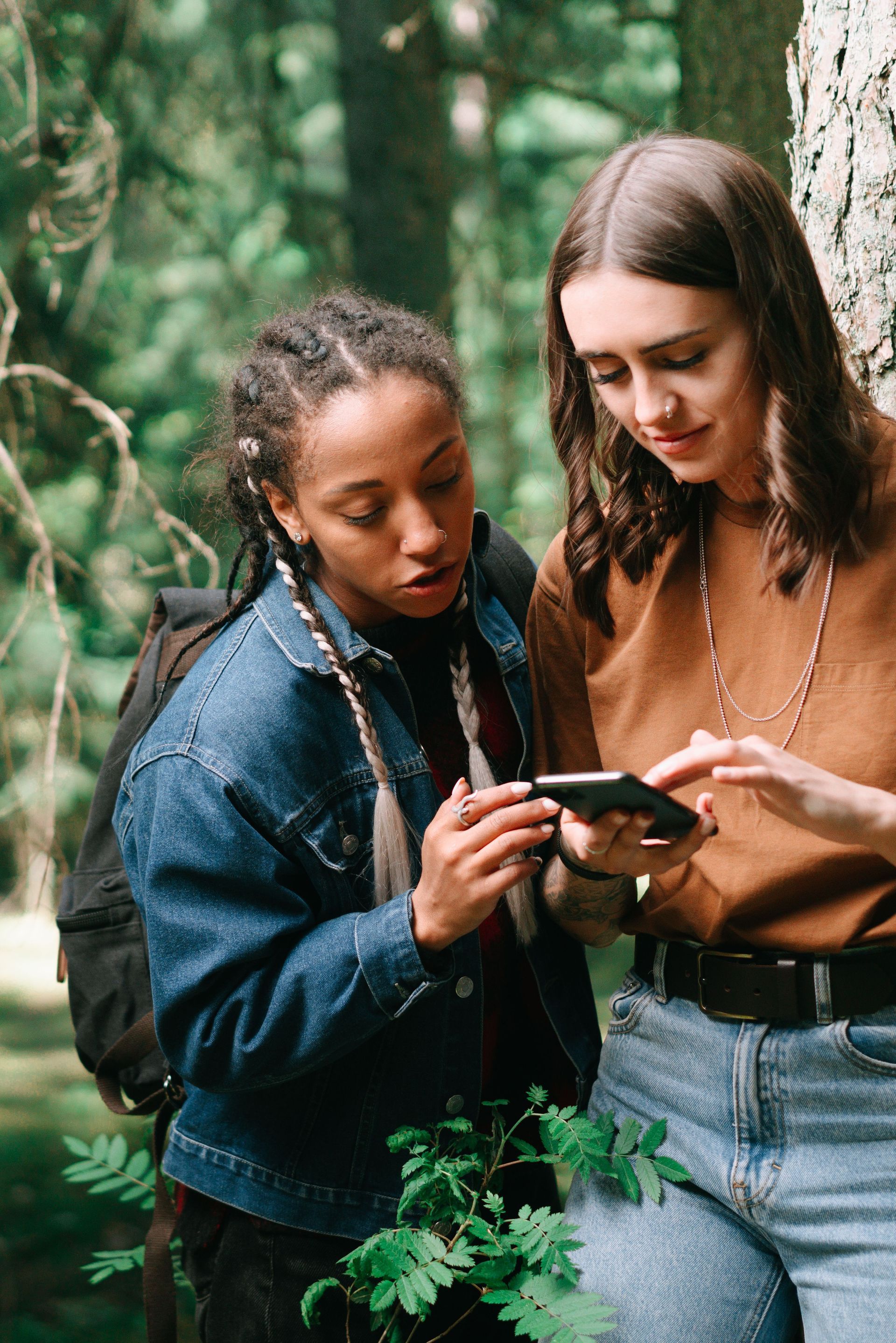 Two people in a forest looking at a smartphone together