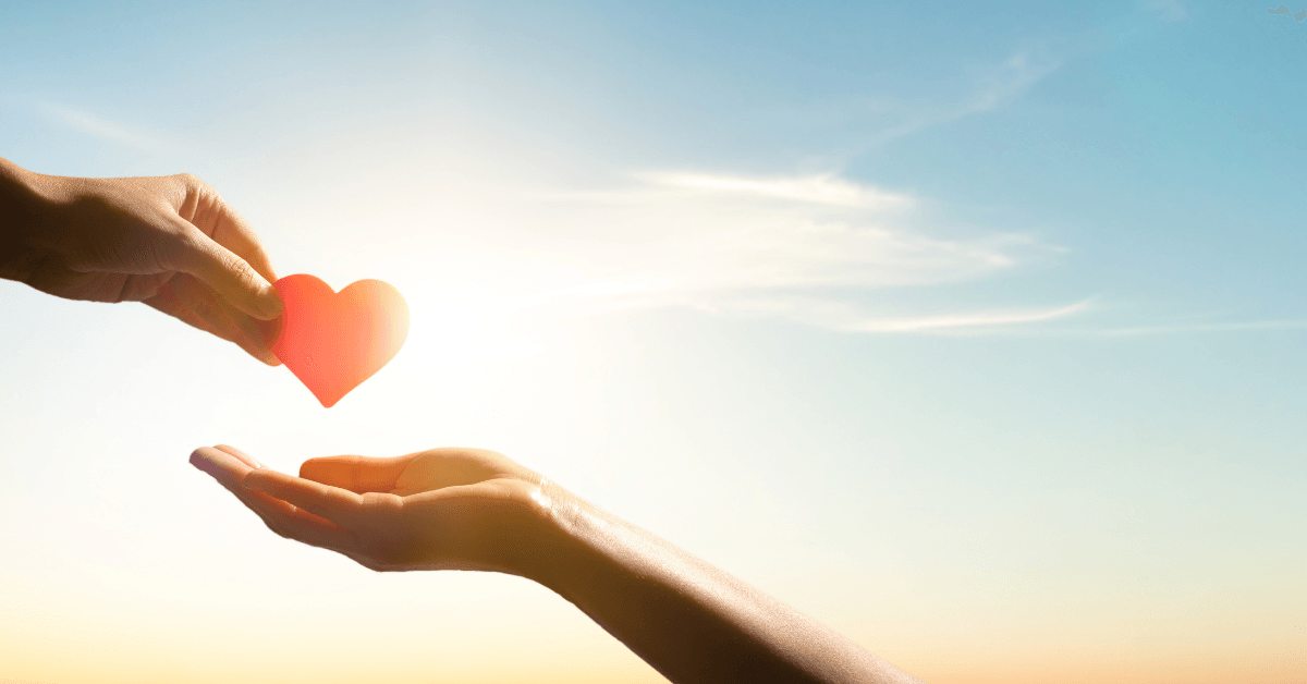 A person is giving a red paper heart to another person.