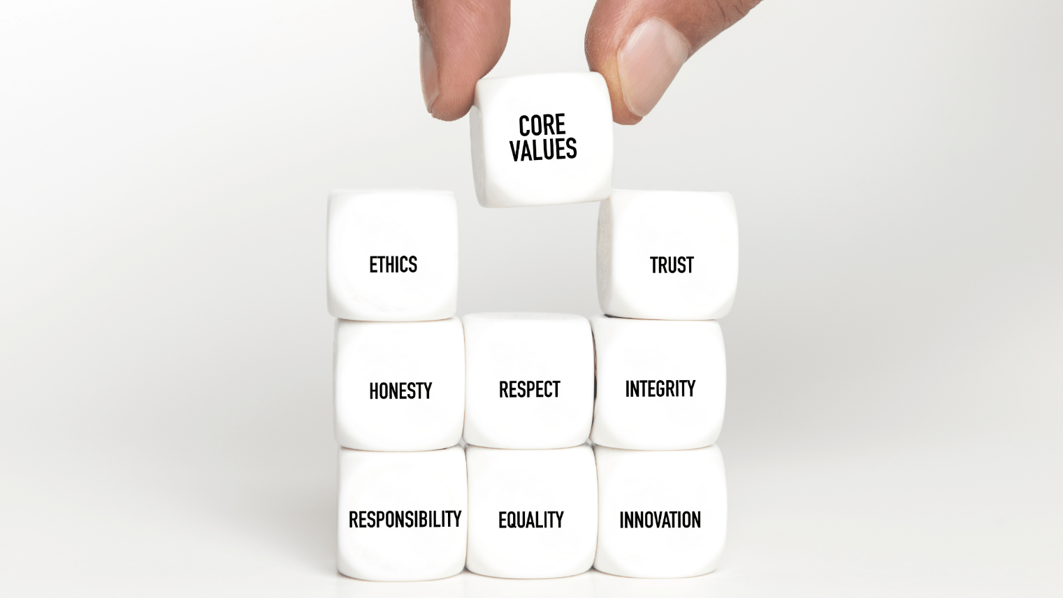 A person placing a cube saying 'Core Values' among a number of other cubes that have different values written on them, such as Integrity, Equality and Respect.