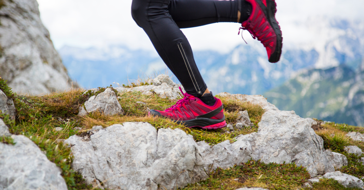 A person in pink sneakers running up a rocky mountain
