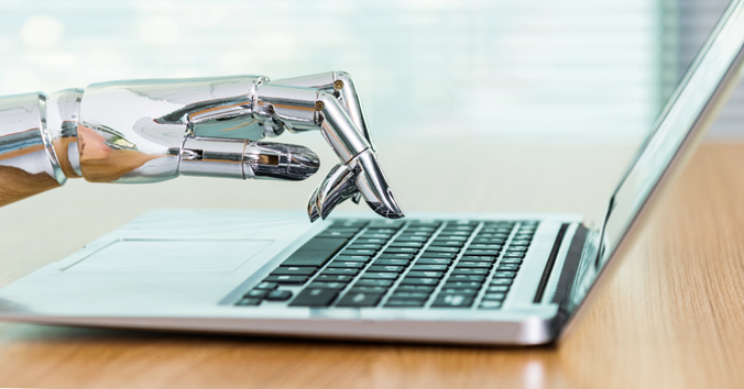 A robotic hand is typing on a laptop computer