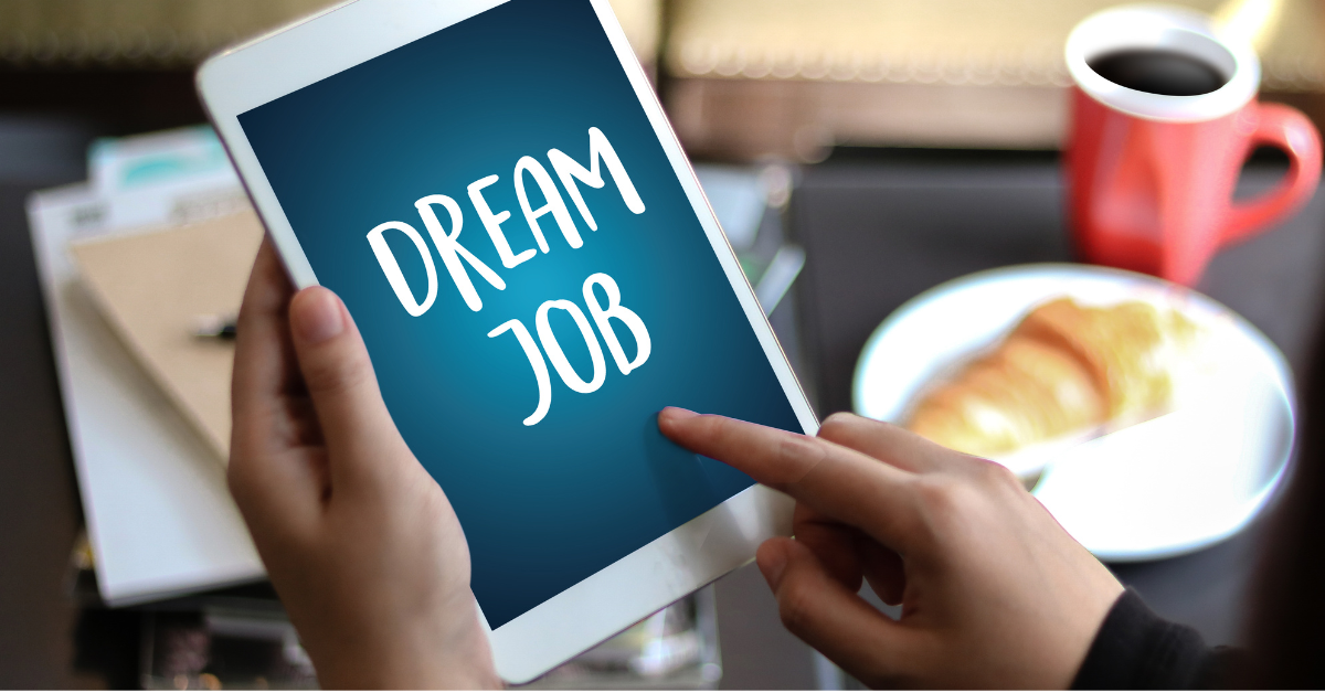 A person sitting in a cafe looking at a tablet that says 'Dream Job'