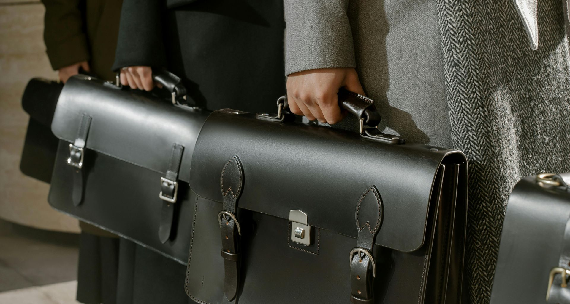 Office workers holding black briefcases and standing in a line 