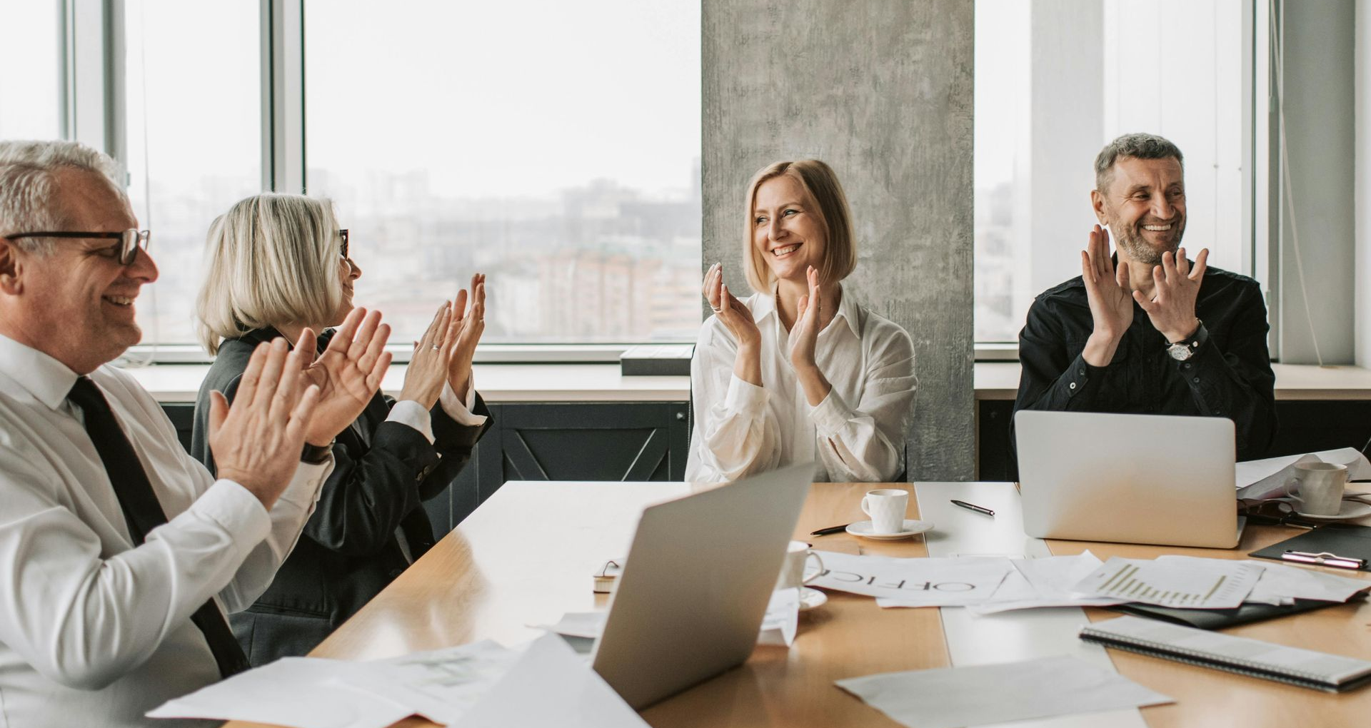 Colleagues sitting around a conference table and clapping their hands