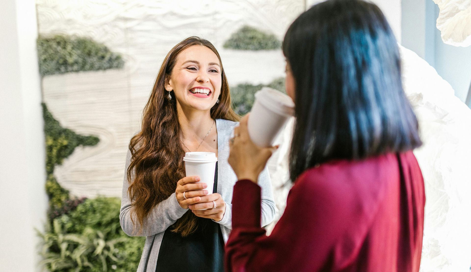 2 colleagues chatting while holding takeaway cups of coffee