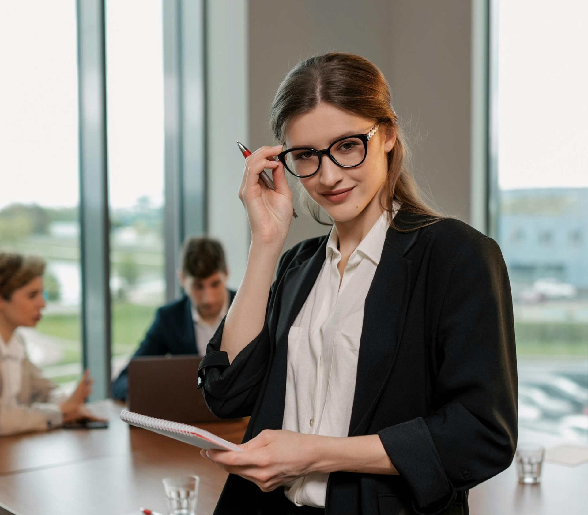 A woman standing in an office with co-workers behind her