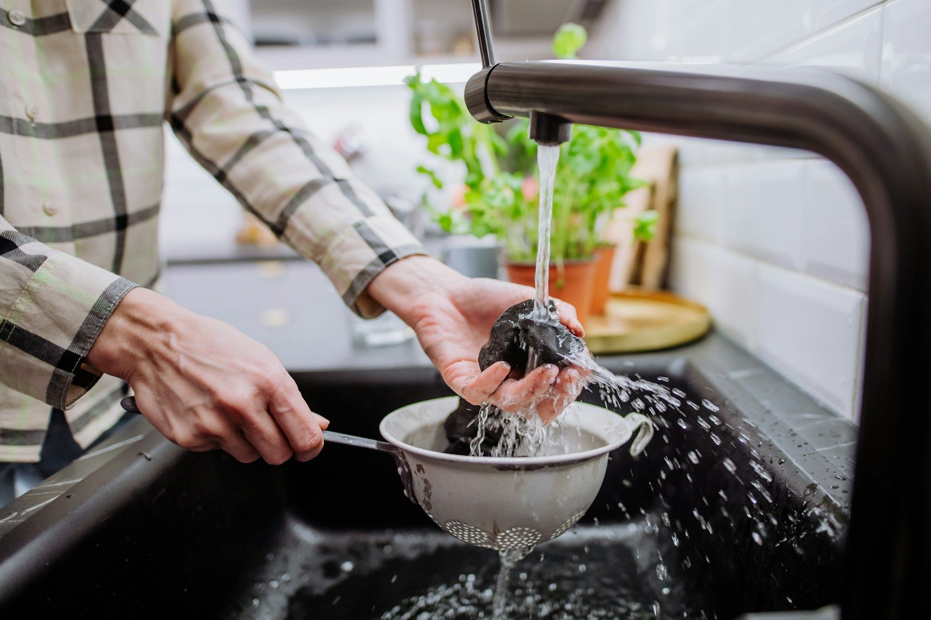 Plumber working under a kitchen sink using a drain cleaning machine.