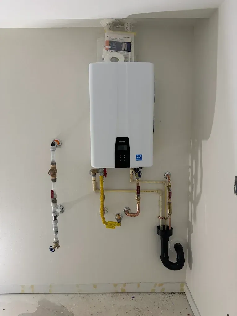 Wall-mounted white water heater with exposed yellow and copper pipes in a utility room.