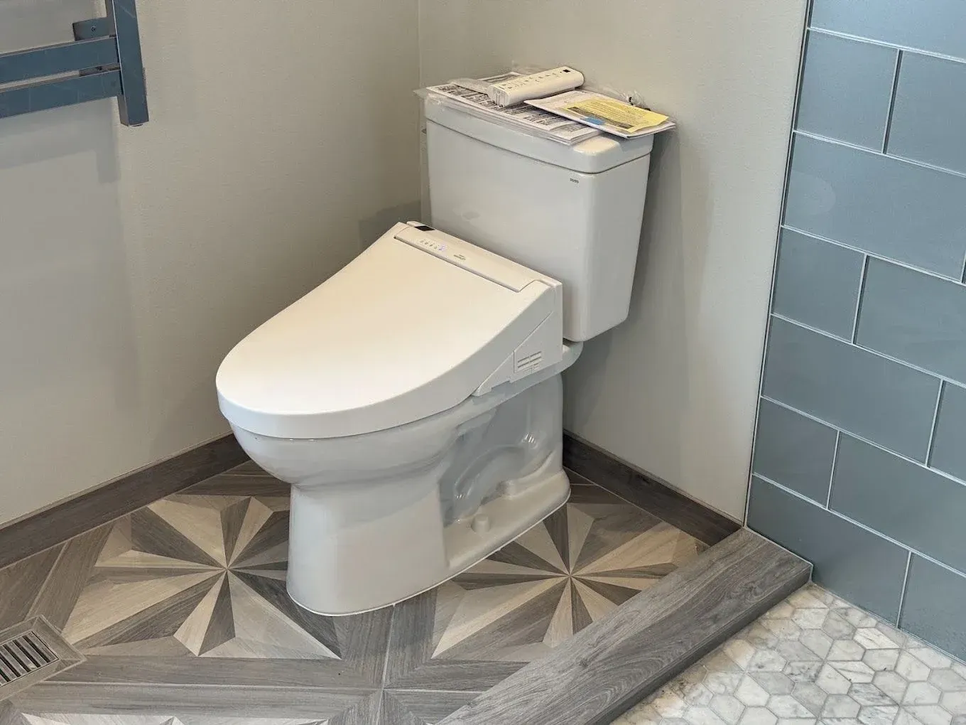 Modern toilet with tank in a small tiled bathroom corner