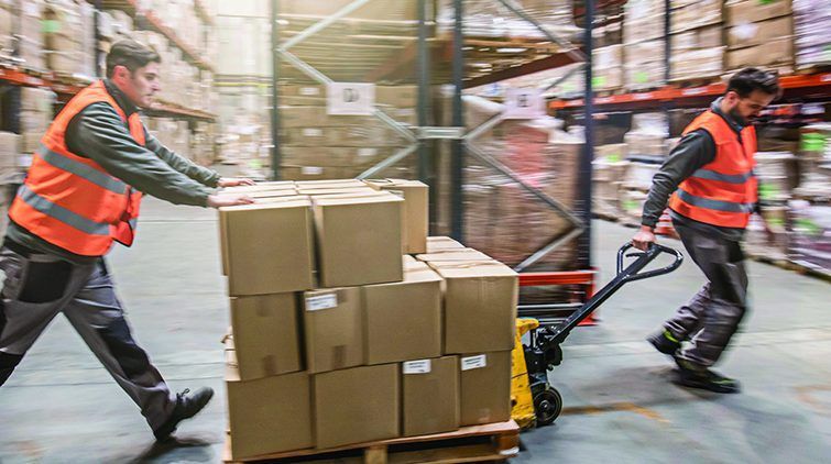 Two men are moving boxes on a pallet in a warehouse.