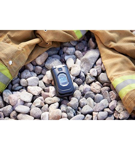 A cell phone is laying on top of a pile of rocks next to a fireman 's jacket.