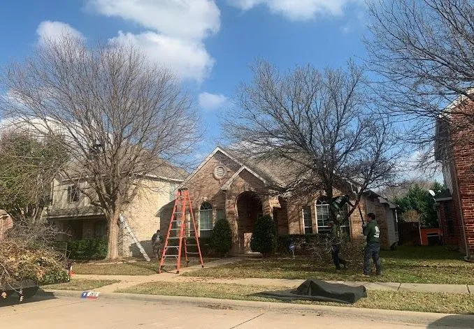 A man is standing in front of a house with a ladder in front of it.