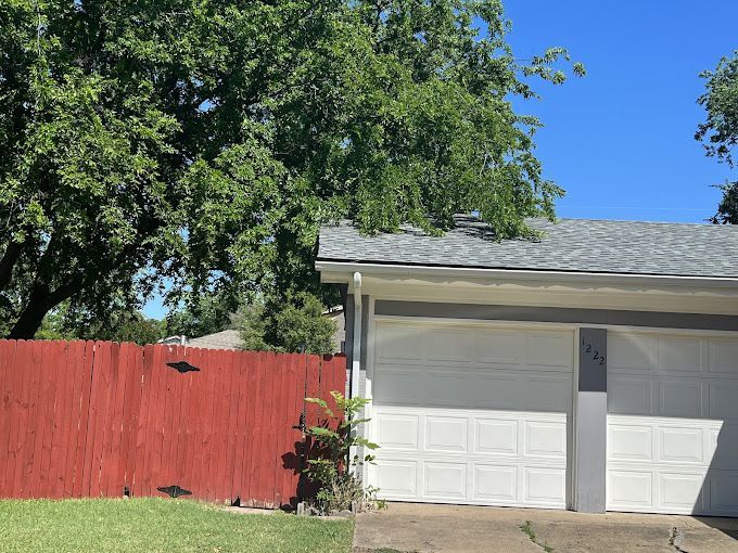 A house with a red fence and a white garage door.