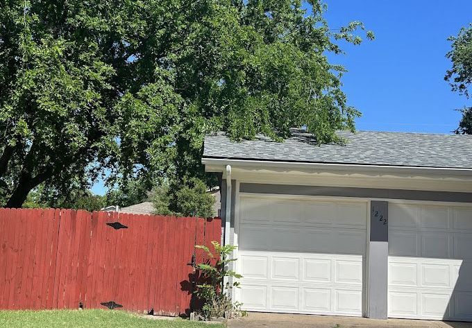 A white garage door with a red fence in front of it.