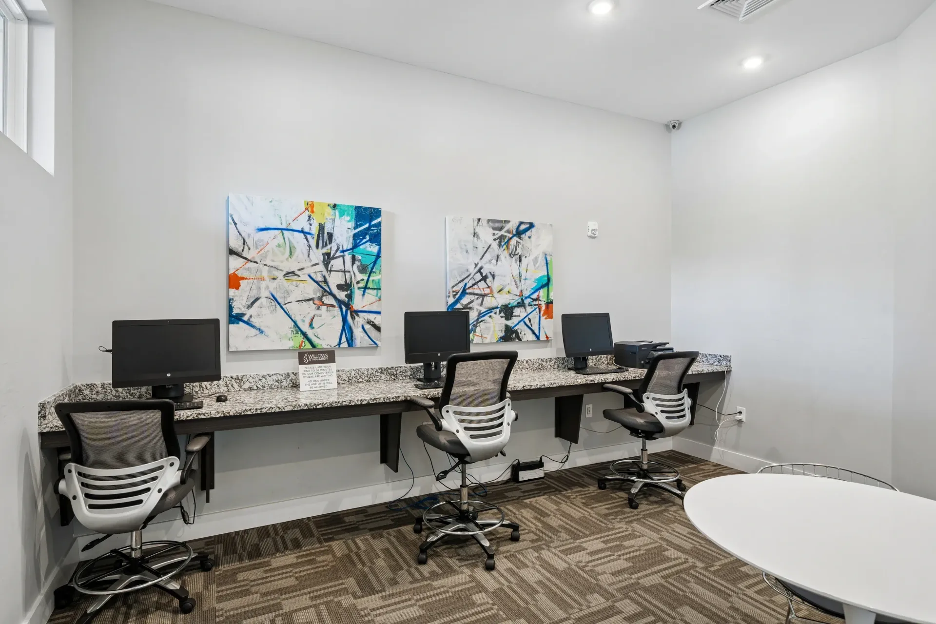 Business center with computers, printer, and seating at Willows at the University in Charlotte, NC.