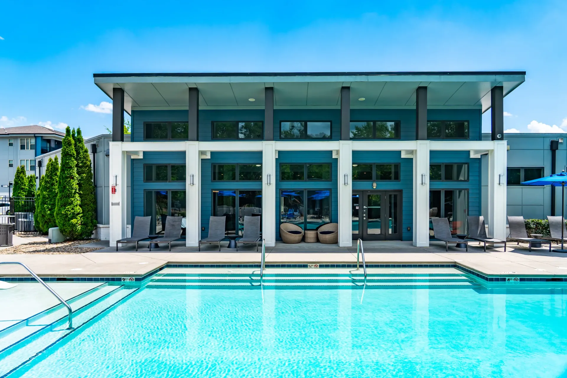 Resort-style swimming pool with lounge chairs and a modern clubhouse at Willows at the University in Charlotte, NC.