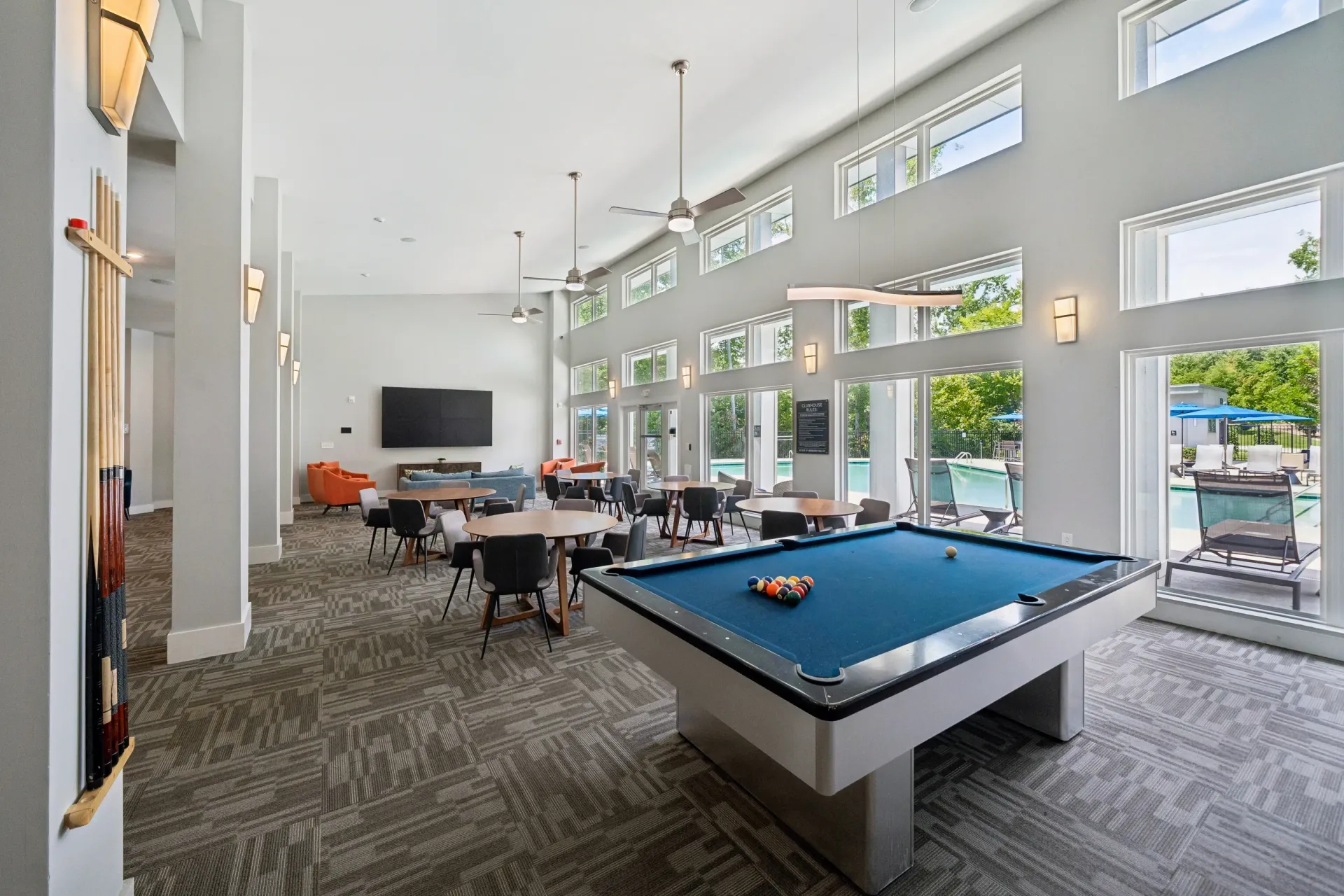 Community lounge with a pool table, seating areas, and pool views at Willows at the University in Charlotte, NC.