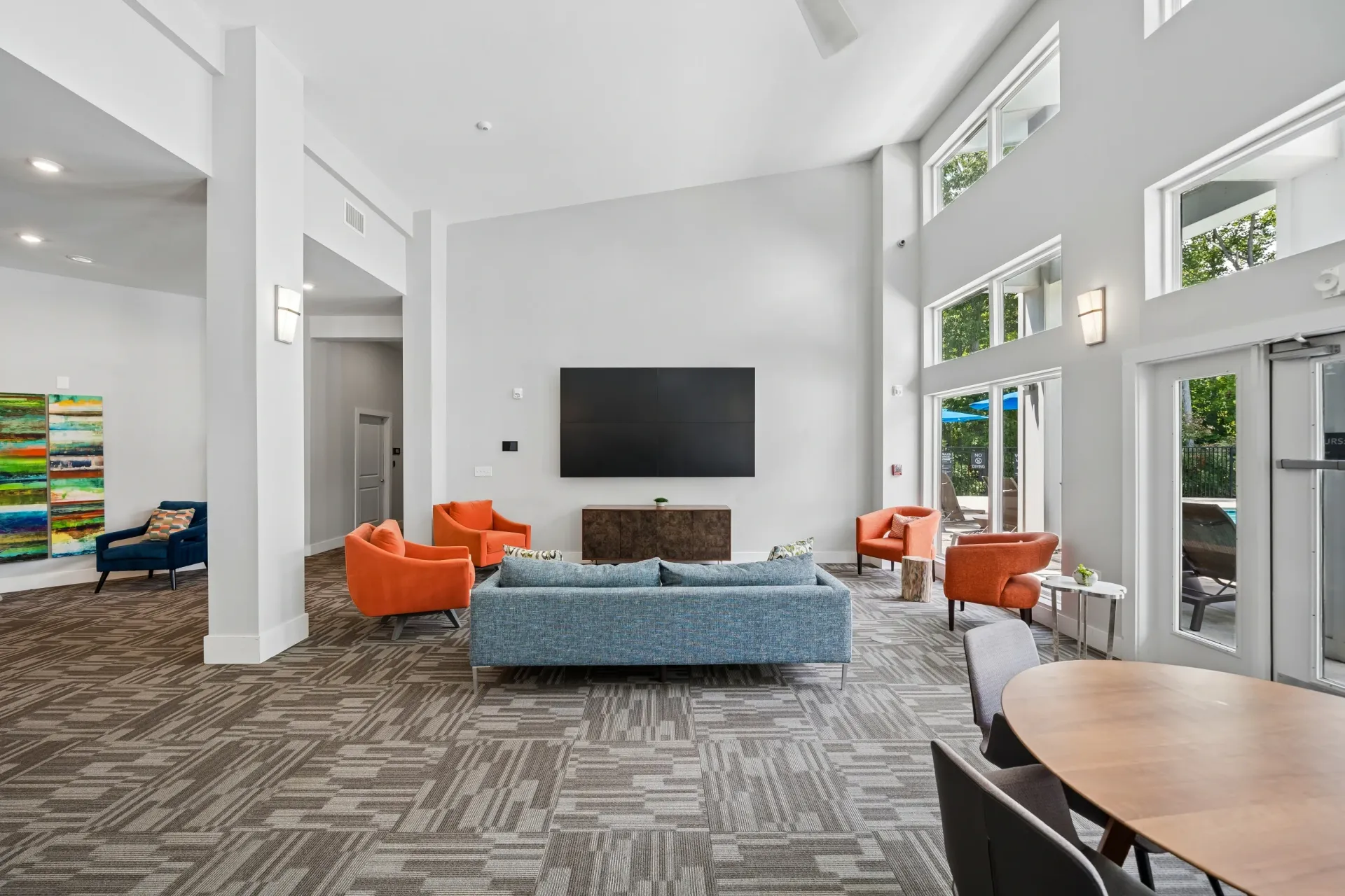 Modern lounge area with a large TV, comfortable seating, and contemporary art at Willows at the University in Charlotte, NC.