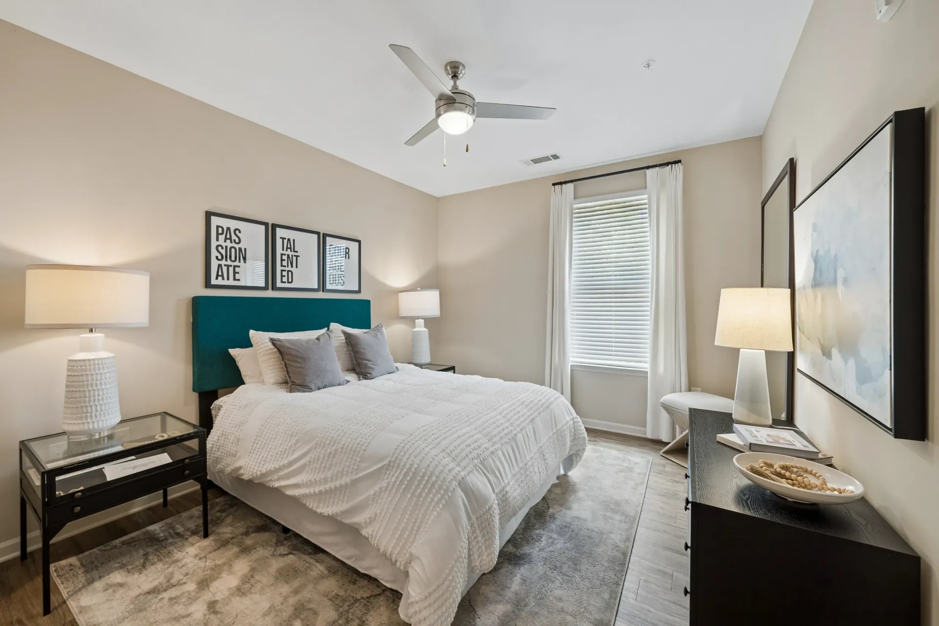 A spacious bedroom with a king-size bed, teal headboard, and modern decor at Willows at the University in Charlotte, NC.