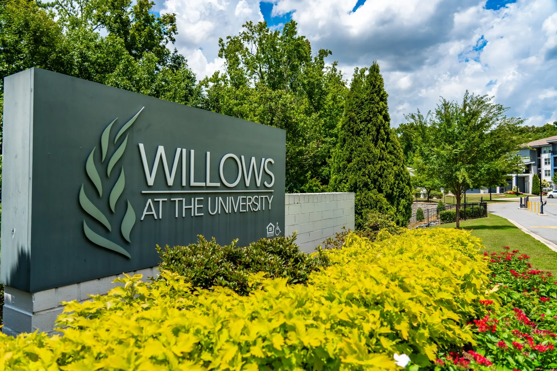 Monument sign for Willows at the University, with landscaping and apartment buildings in the background at Willows at the University in Charlotte, NC.