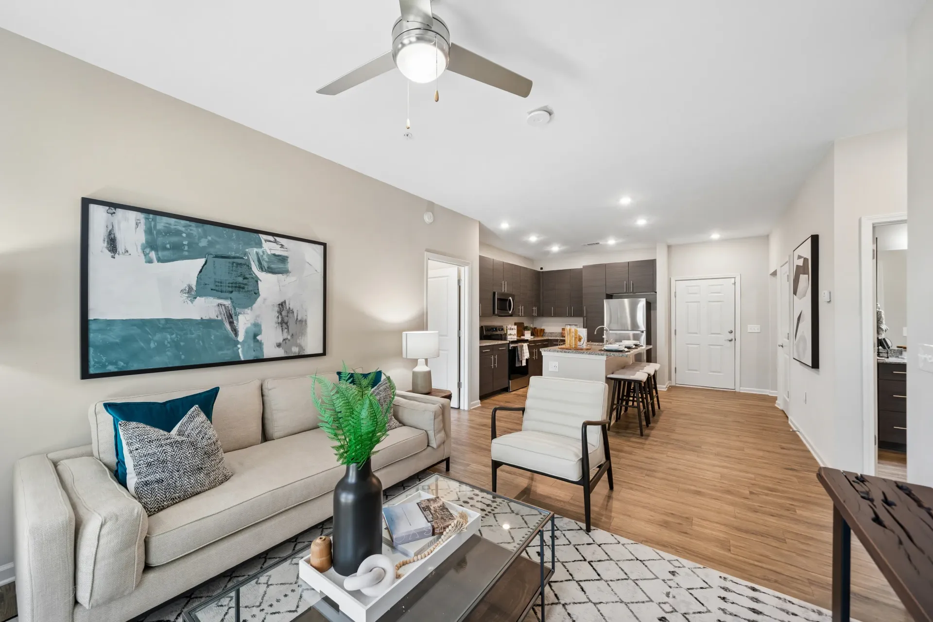 Modern living room and open kitchen with island and bar stools at Willows at the University in Charlotte, NC.