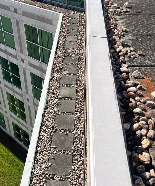 Rooftop with weathered tiles covered in moss, near a window and air conditioning unit.