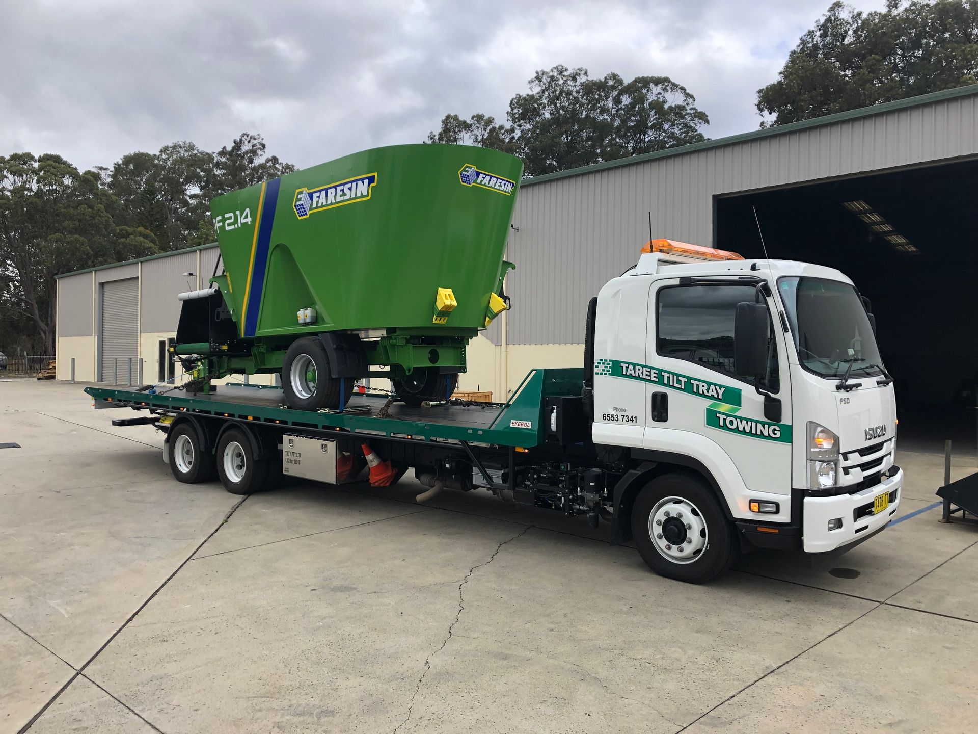 A Tow Truck With An Excavator On The Back Of It — Taree Tilt Tray Towing In Coolongoolook, NSW