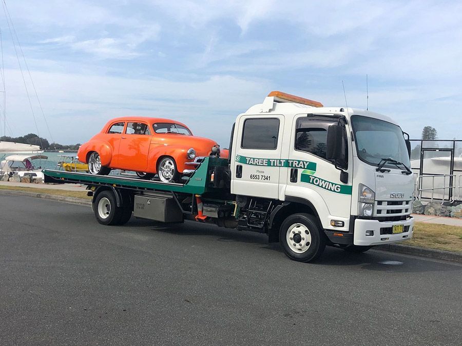 Two Tow Trucks Are Parked Next To Each Other In A Grassy Field — Taree Tilt Tray Towing In Pampoolah, NSW
