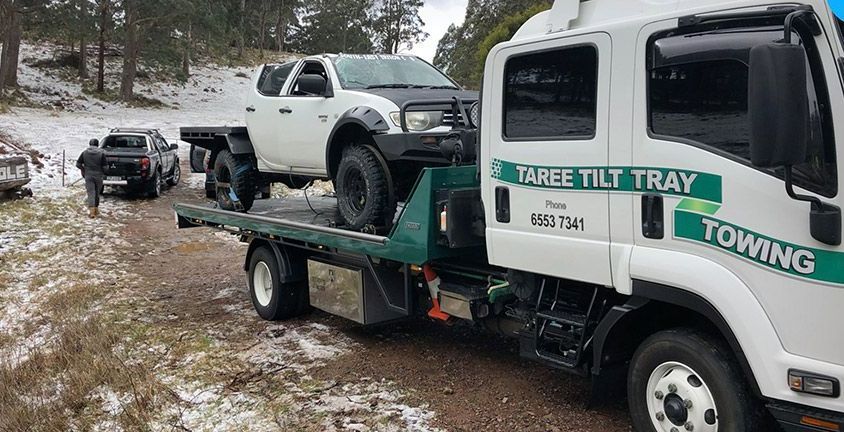 A Tow Truck is Towing a White Truck and a Black Truck — Taree Tilt Tray Towing In Taree, NSW