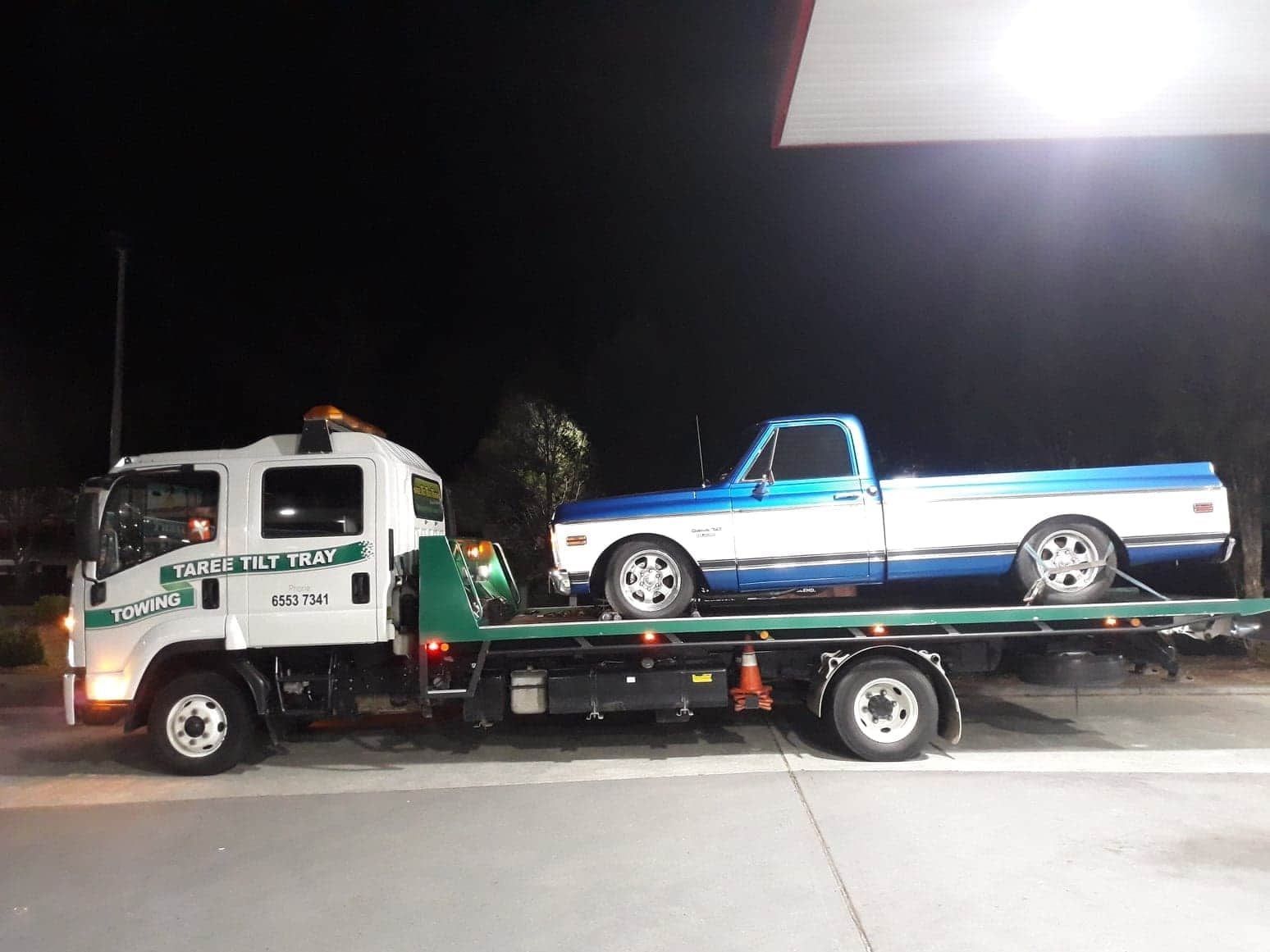 A Tow Truck Is Towing A Car On The Back Of It — Taree Tilt Tray Towing In Pampoolah, NSW