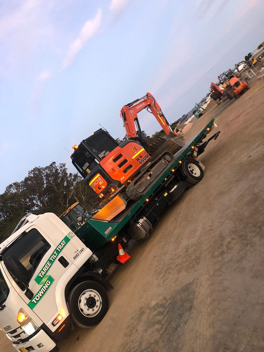 A Tow Truck With an Excavator on the Back of It — Taree Tilt Tray Towing In Pampoolah, NSW