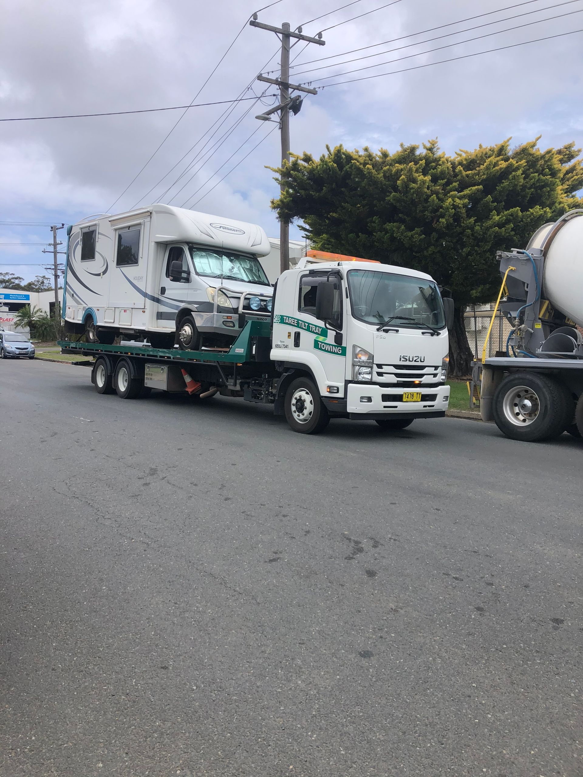 A Tow Truck Is Carrying A Tractor On A Trailer — Taree Tilt Tray Towing In Pampoolah, NSW