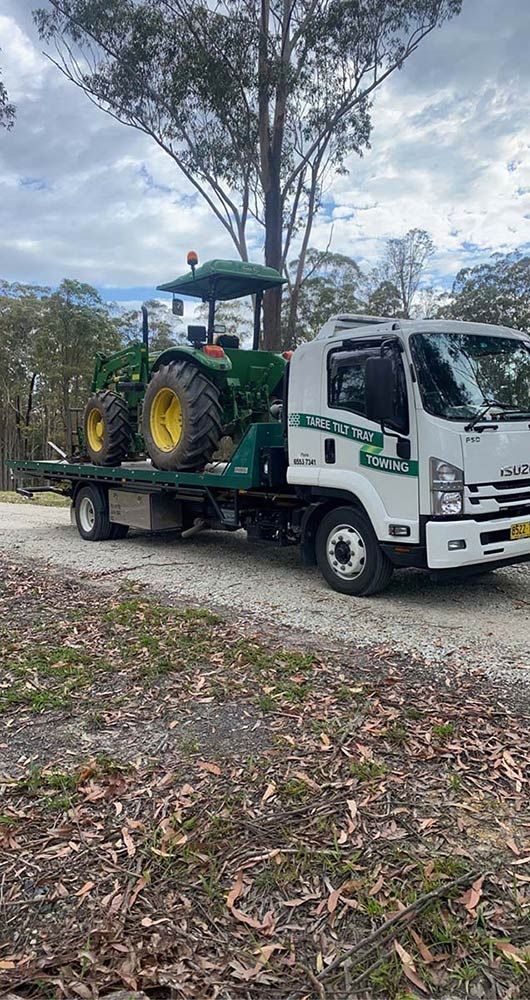 A Tow Truck is Carrying a Tractor on the Back of It — Taree Tilt Tray Towing In Coolongoolook, NSW