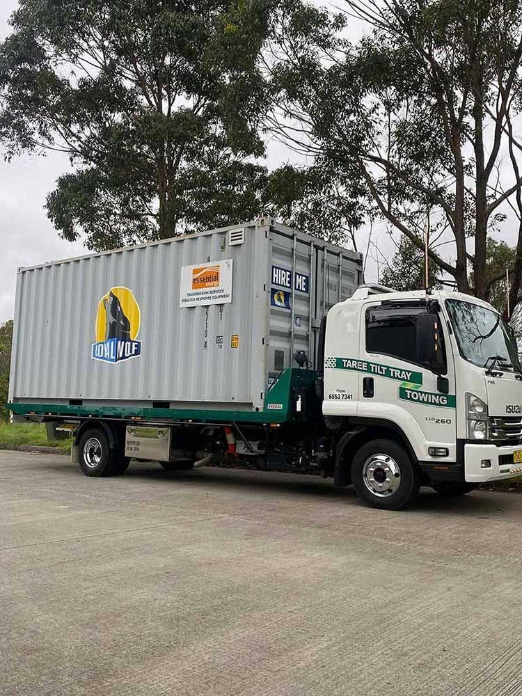 A White Truck With A Container On The Back Is Parked In A Parking Lot — Taree Tilt Tray Towing In Old Bar, NSW