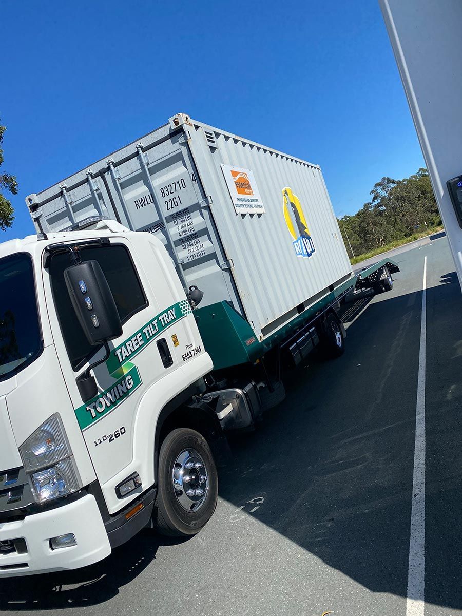 A White Truck With a Container on the Back is Parked on the Side of the Road — Taree Tilt Tray Towing In Taree, NSW