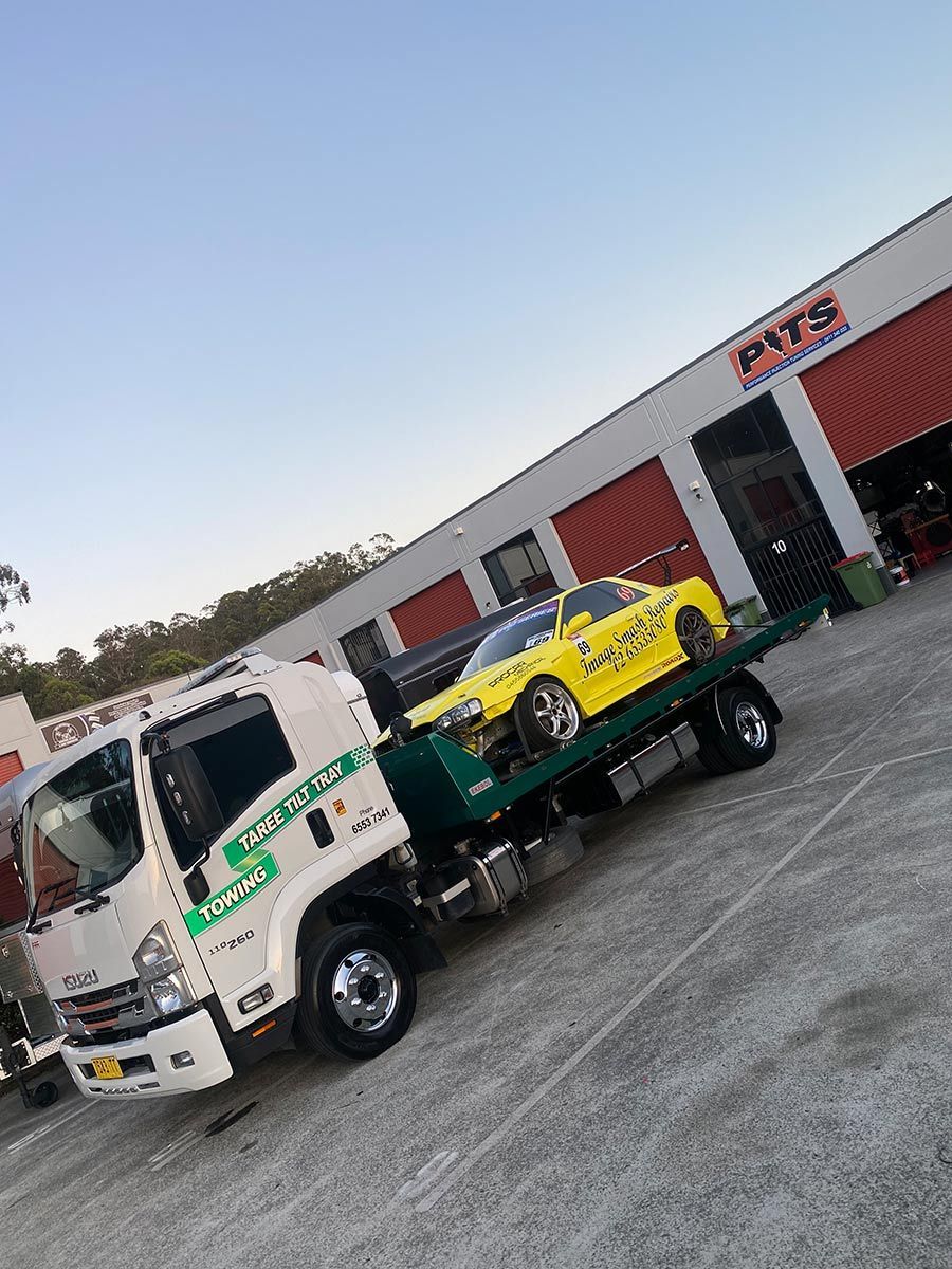 A Yellow Car is on the Back of a Tow Truck — Taree Tilt Tray Towing In Hallidays Point, NSW