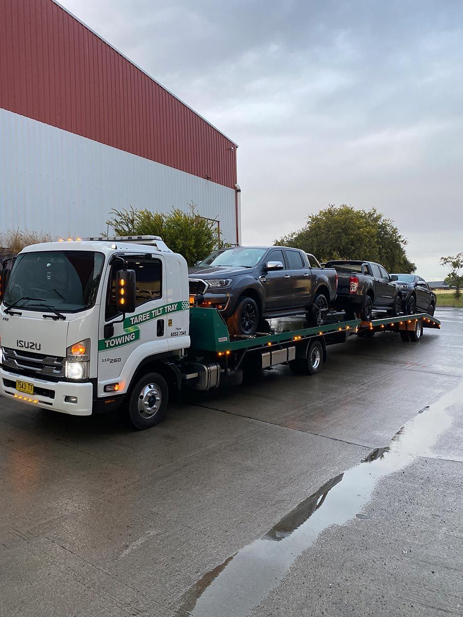 A Tow Truck is Carrying a Row of Cars on a Flatbed Trailer — Taree Tilt Tray Towing In Tuncurry, NSW
