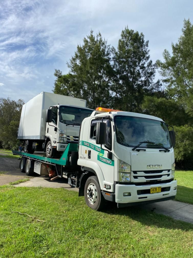 A White Tow Truck Is Carrying A White Truck On A Flatbed Trailer — Taree Tilt Tray Towing In Taree, NSW