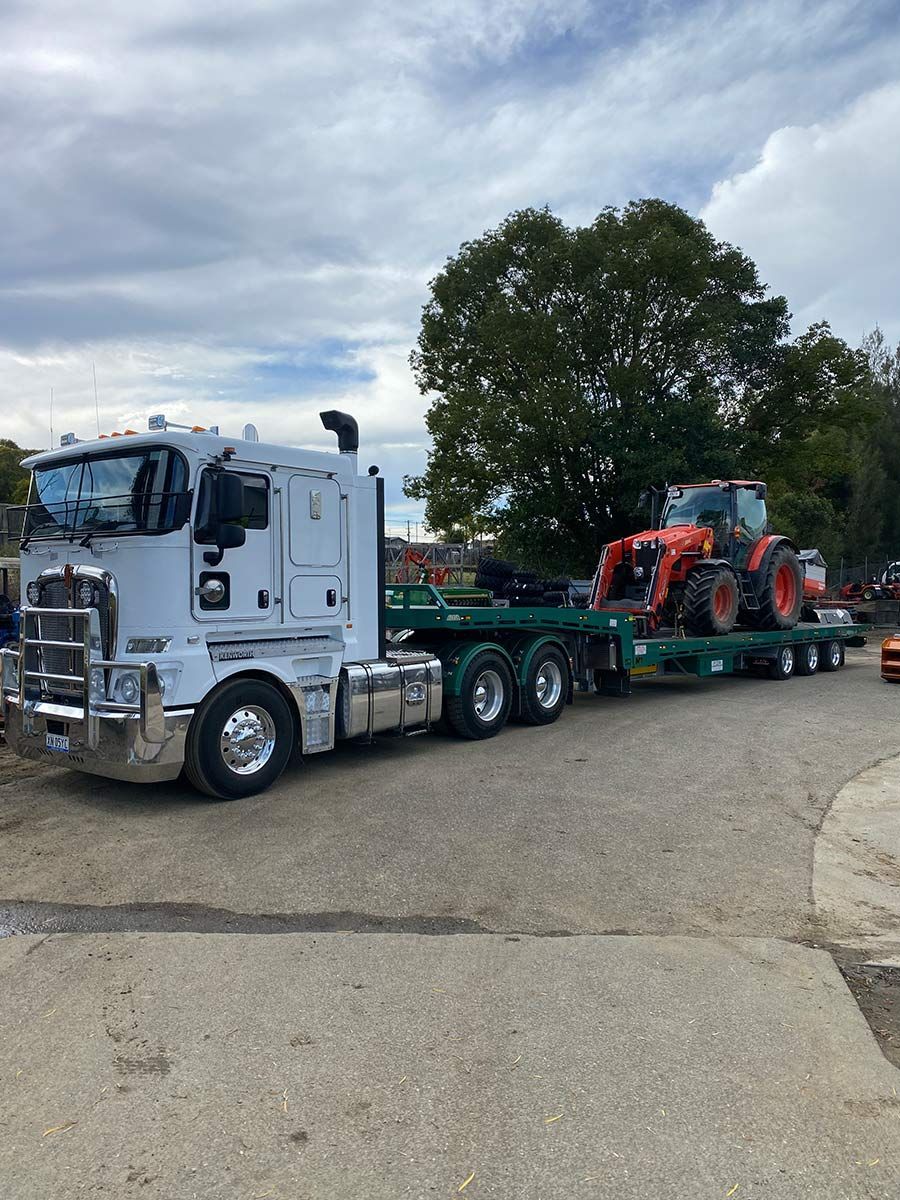 A Semi Truck is Carrying a Tractor on a Trailer — Taree Tilt Tray Towing In Taree, NSW