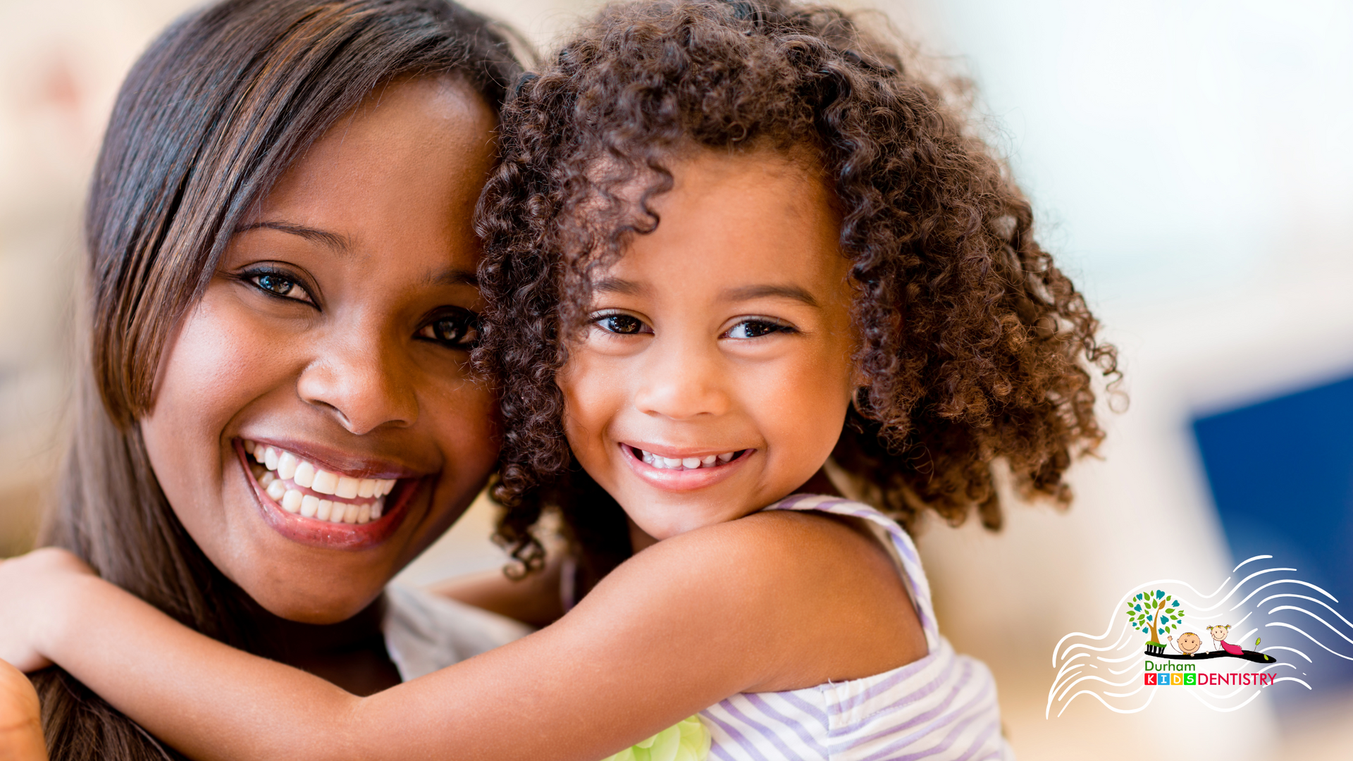 A woman is holding a little girl in her arms and they are smiling for the camera.