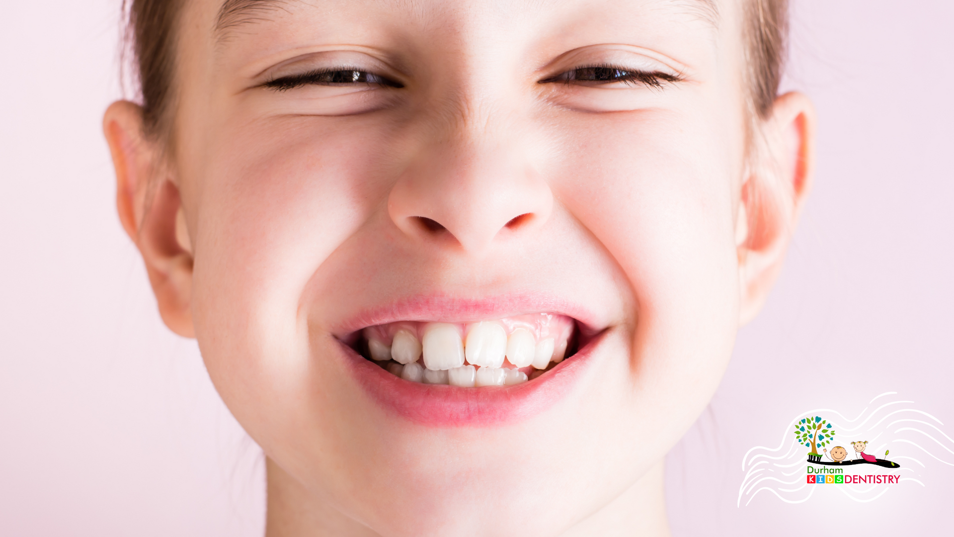 A close up of a young girl smiling with her eyes closed.