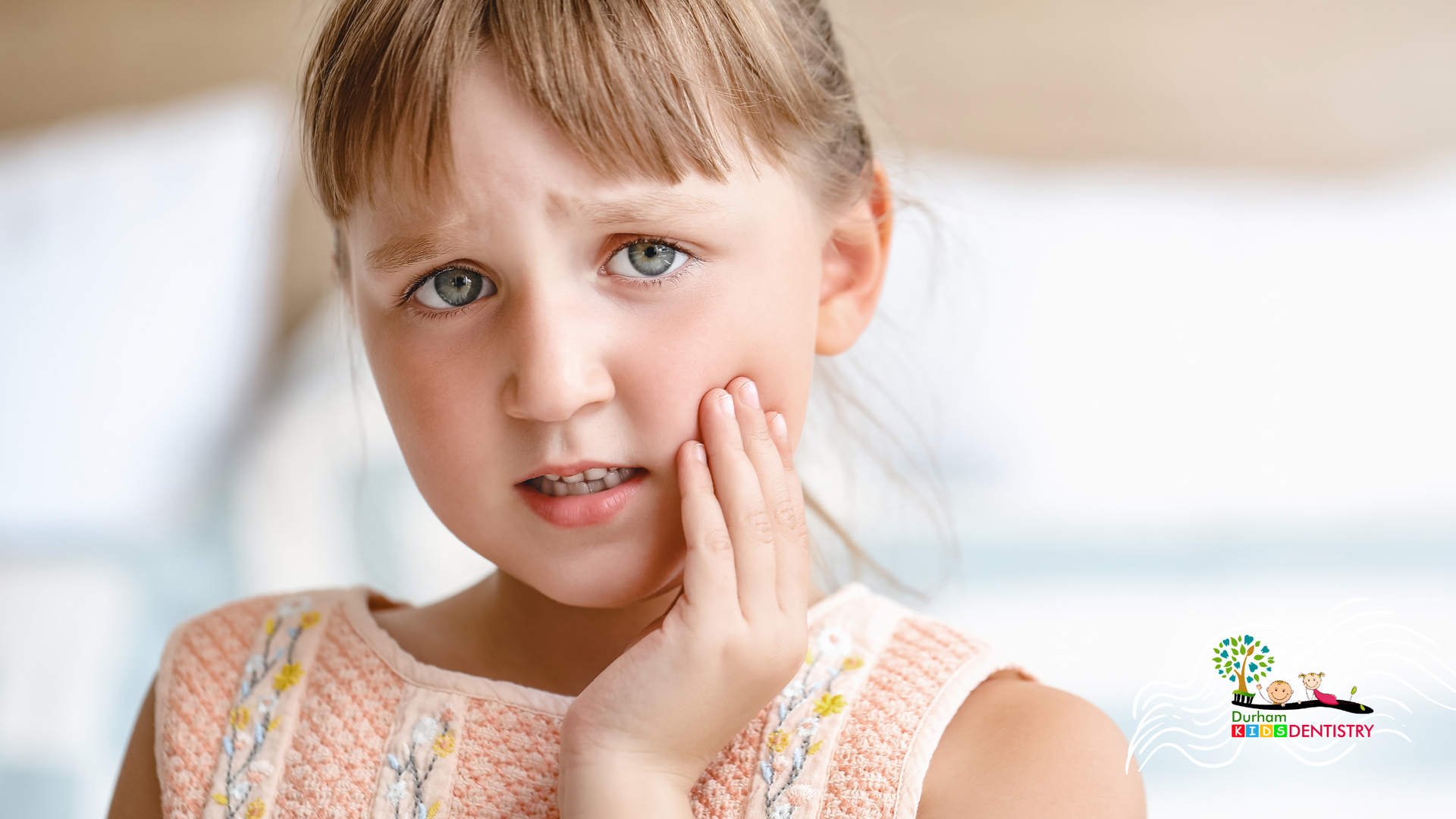 A little girl is holding her face in pain because of a toothache.