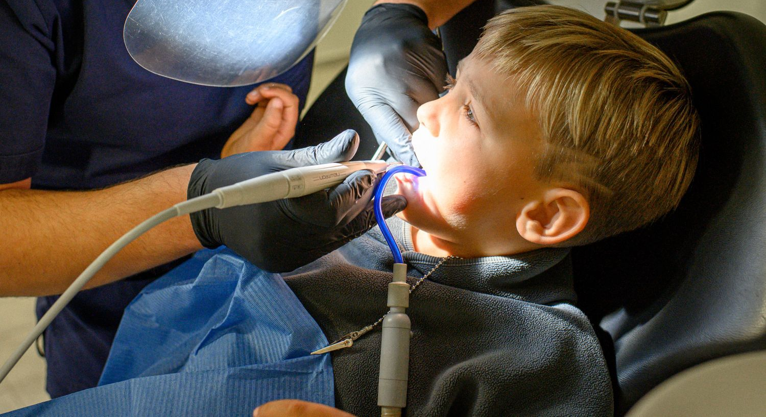 Smiling child reclining in a blue dental chair at a clinic