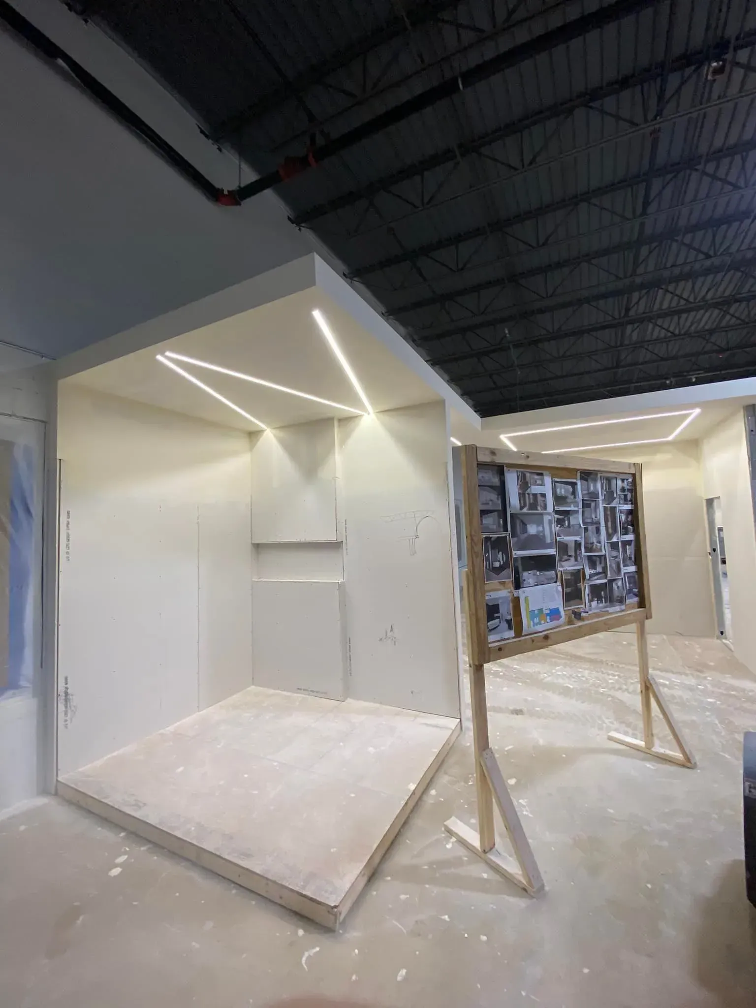 Gallery installation of white geometric booths and hanging boards in an indoor exhibition space