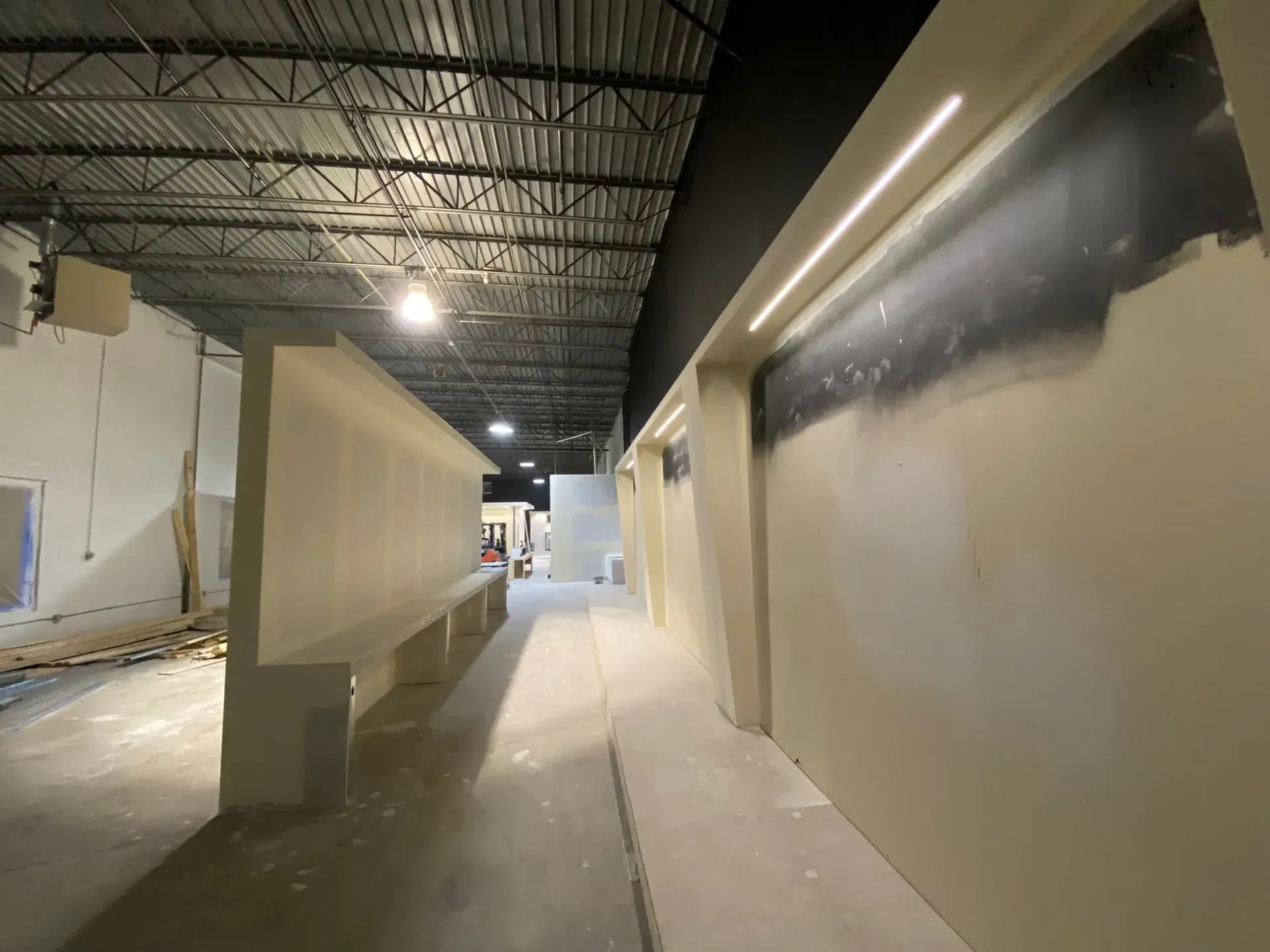 Indoor hallway with beige walls and unfinished construction under industrial ceiling lights
