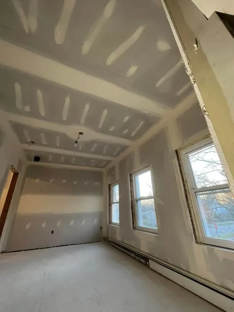 Empty unfinished room with drywall, windows, and exposed ceiling seams.
