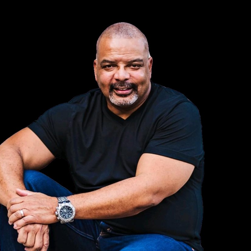 Dave a board member. A man in a black t-shirt and blue jeans, smiling and looking toward the camera against a solid black background.