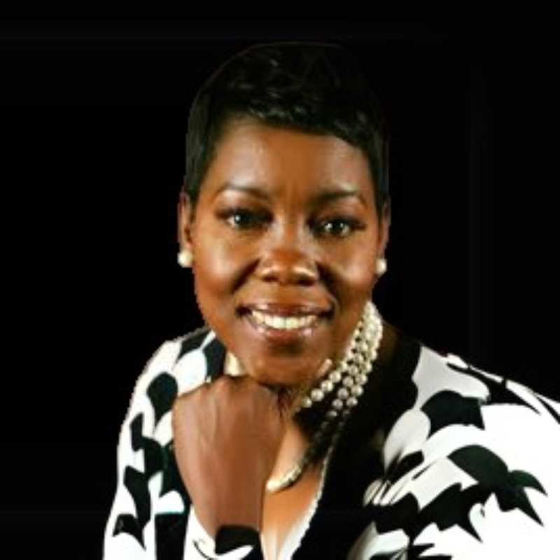 Angelique a board member. A person wearing a patterned black-and-white top and pearl necklace rests their chin on their hand against a black background.